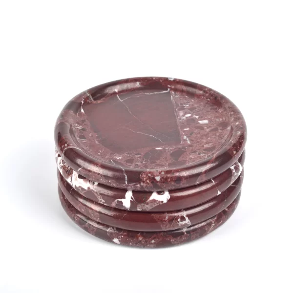 Four small round burgundy marble trays with stunning natural red patches and white veining, stacked together, polished to a smooth and reflective finish.