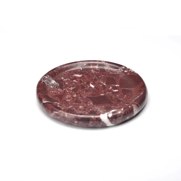 Side view of a round burgundy marble tray highlighting its polished edges and veining patterns.