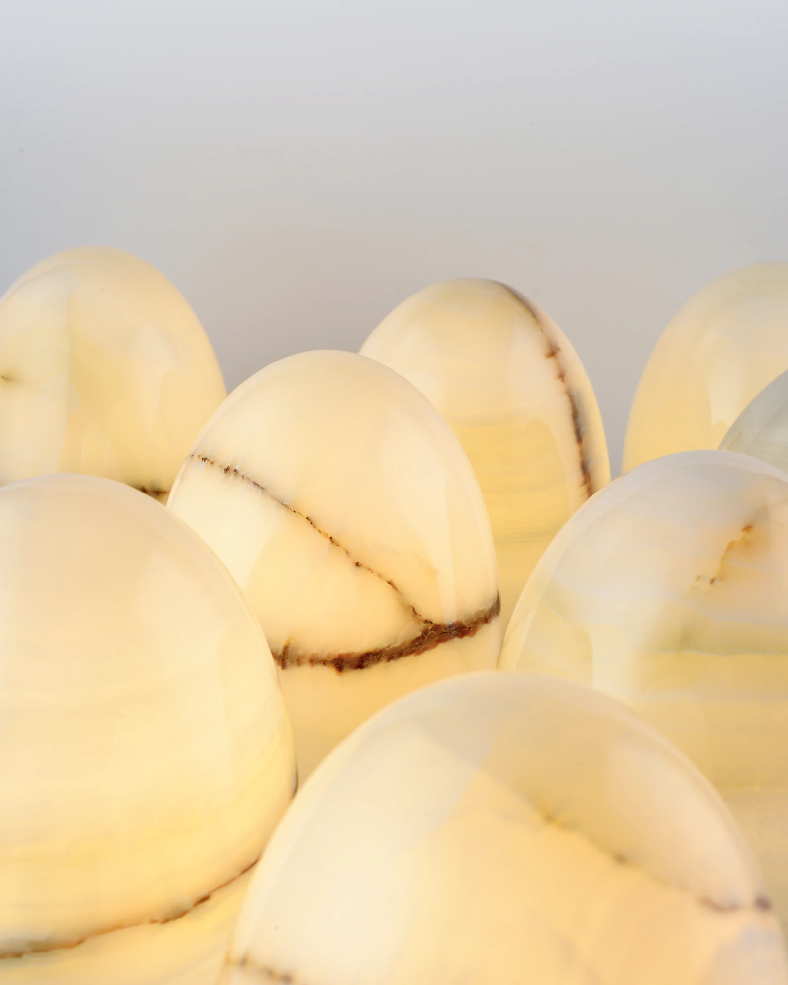 Multiple Egg-Shaped Onyx Tap Lamps with unique natural veins, illuminated close-up highlighting the stone's distinctive texture