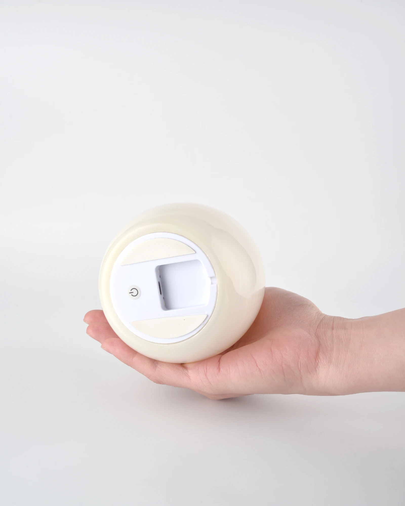 Compact and delicate Egg-Shaped Onyx Tap Lamp placed horizontally in the palm, showing the switch and charging port at the bottom