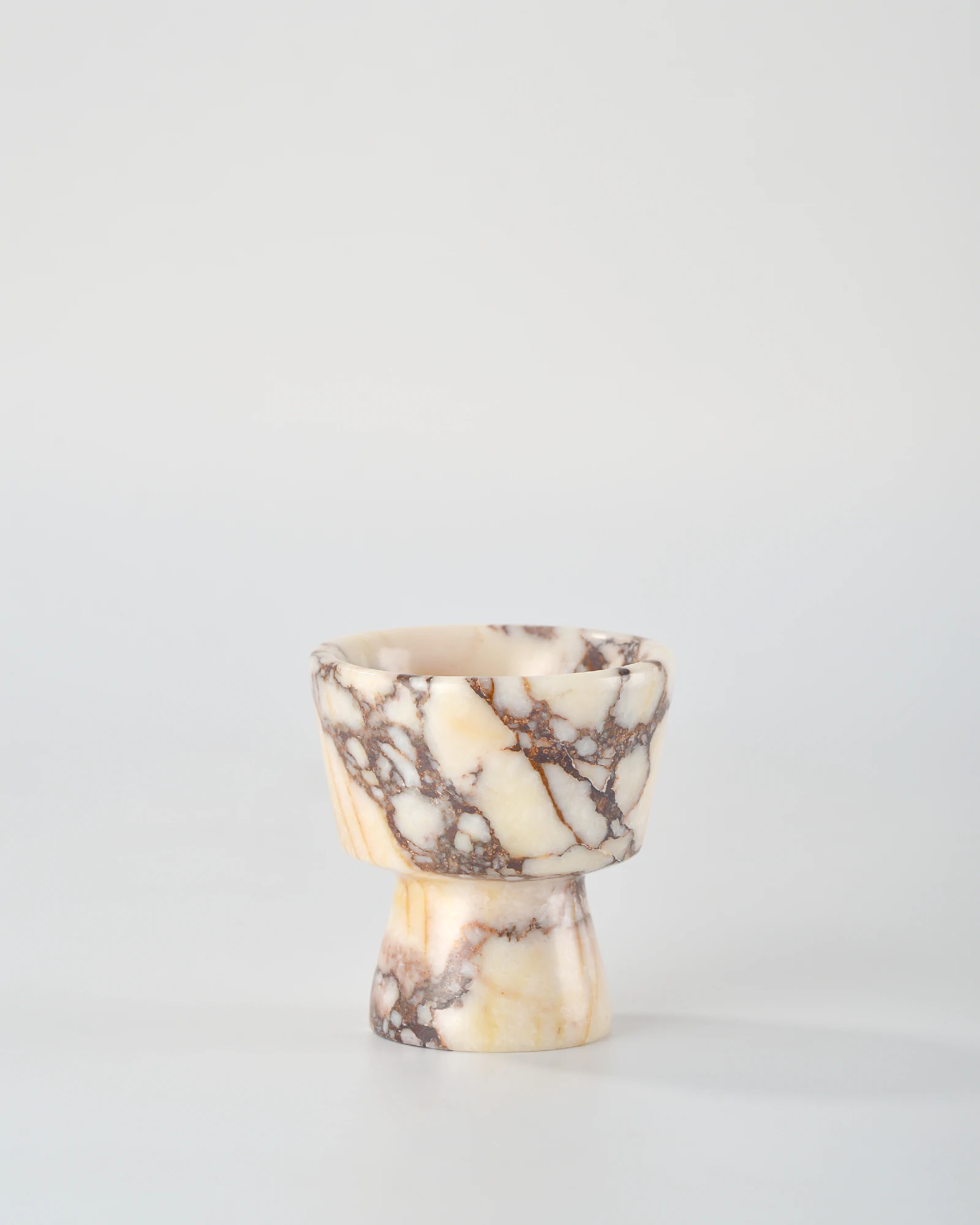 Calacatta Marble candle holder shaped like a geometric combination, with bold purple veining throughout