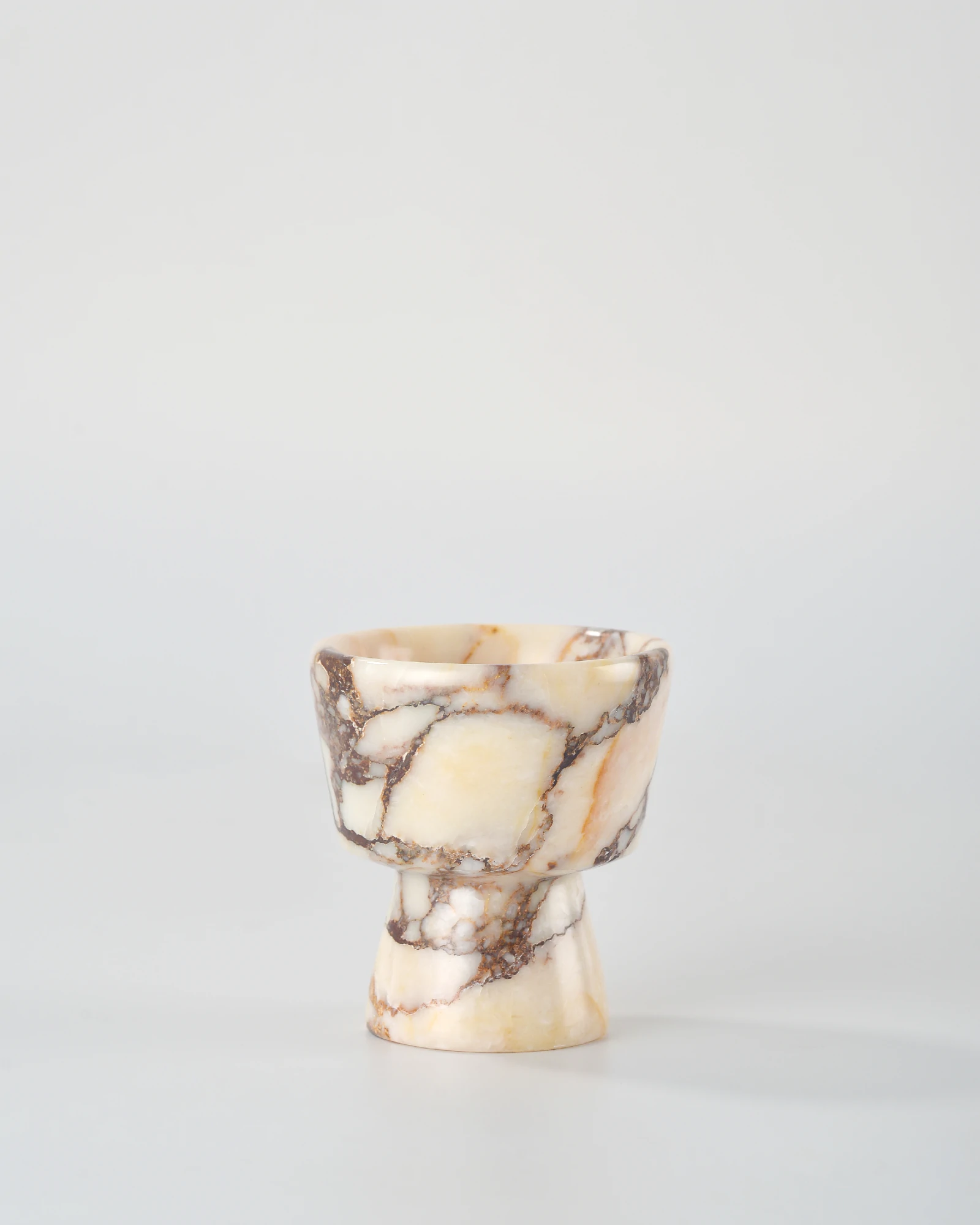 Calacatta Marble candle holder with intricate brown-red veining on beige stone, inspired by geometric shapes