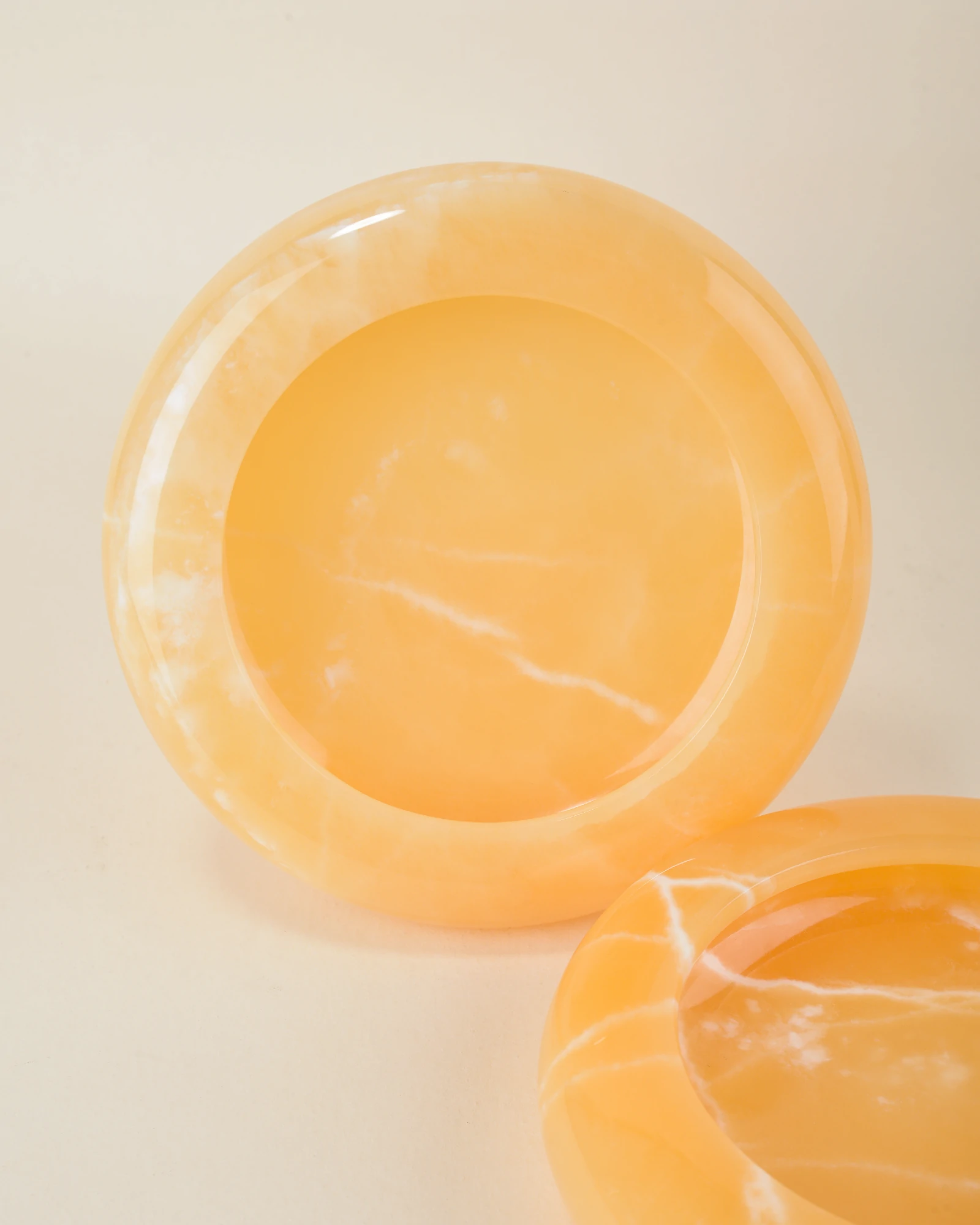 Detailed view of multiple Round Orange Onyx Ashtrays with white natural veins and smooth finishes
