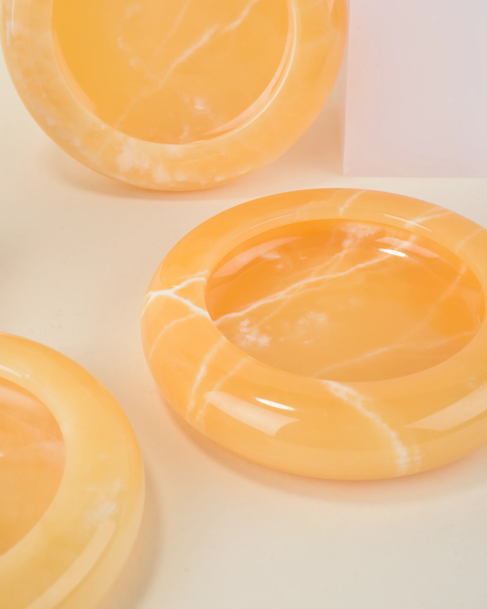 Close-up of handcrafted Round Orange Onyx Ashtrays with polished surfaces and natural white veining