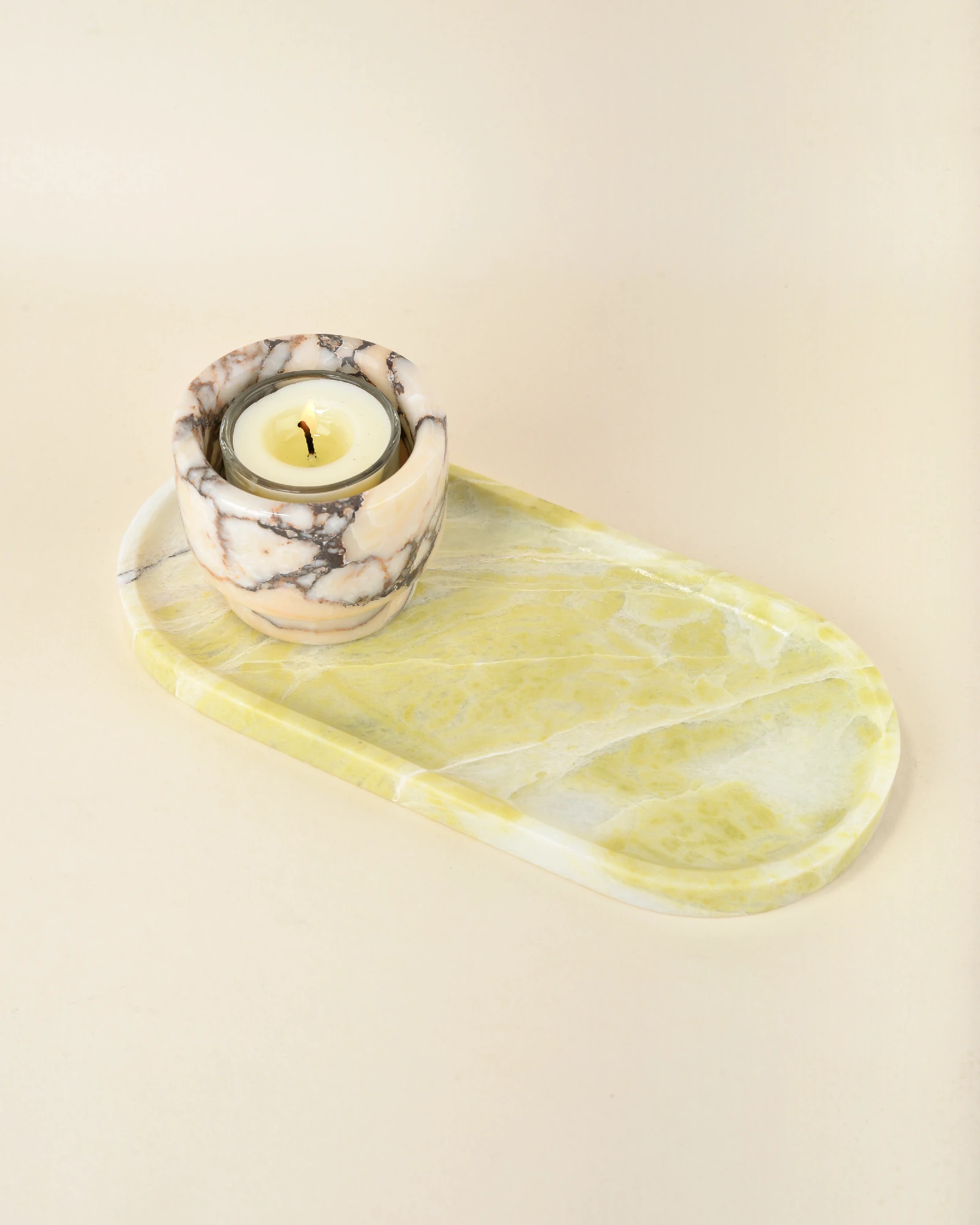 A candle holder placed on the elegant Oval Yellow Marble Tray with natural yellow and green veining