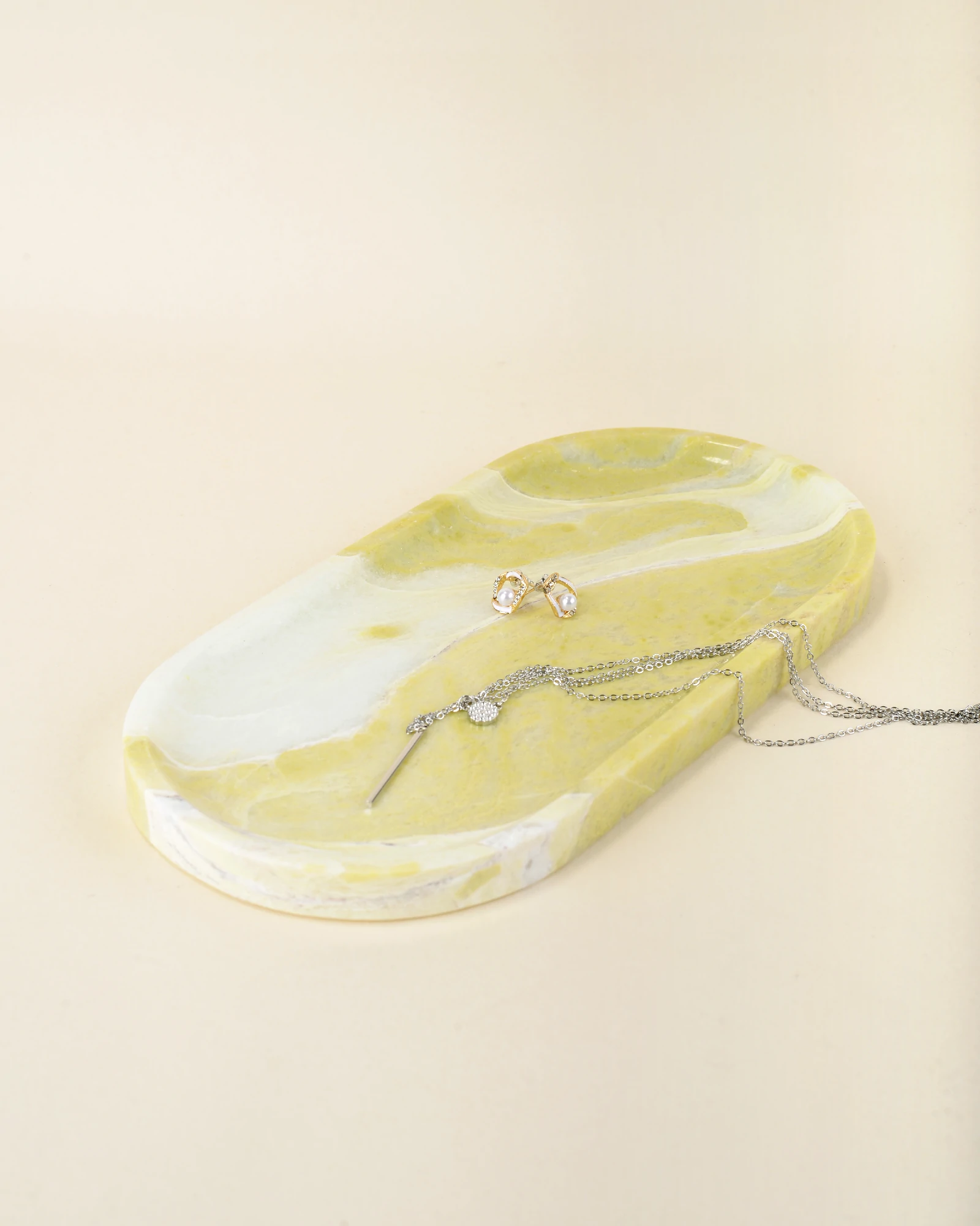 Jewelry pieces placed on the handcrafted Oval Yellow Marble Tray with polished finish