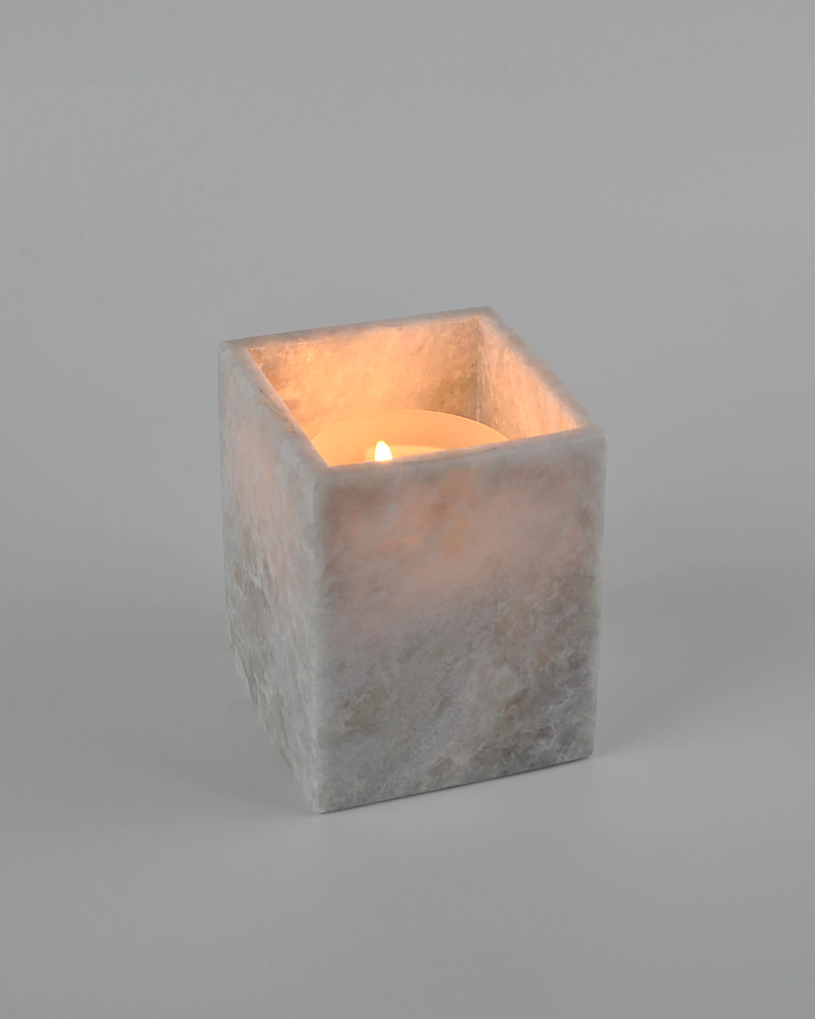 Blueish Crystal Marble Candle Holder with a lit candle inside, reflecting warm light on polished marble surface