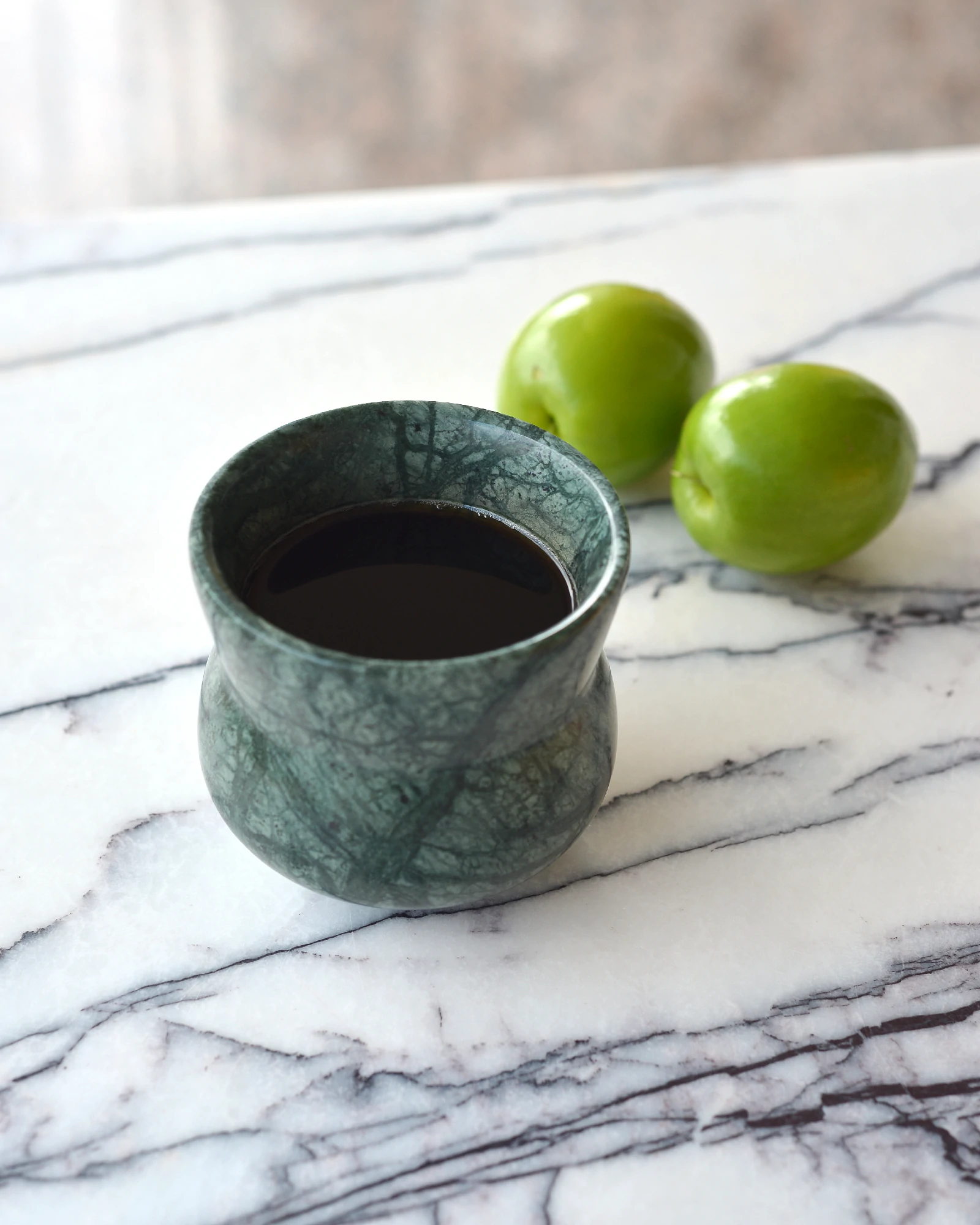 Indian Green Marble Coffee Cup with coffee, placed on a white marble tabletop, highlighting its polished surface and organic veining
