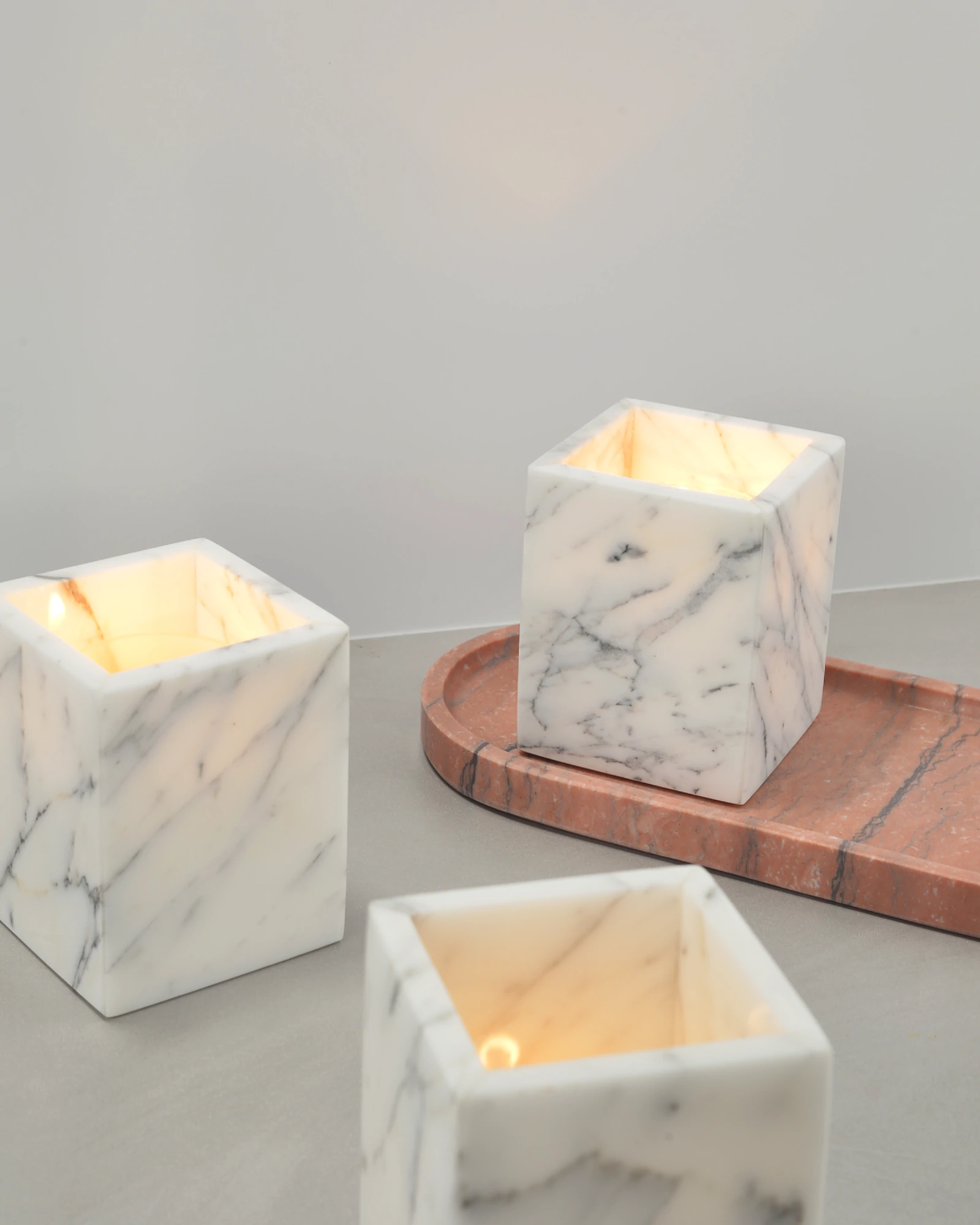 Lit marble candle holders paired with a red marble tray