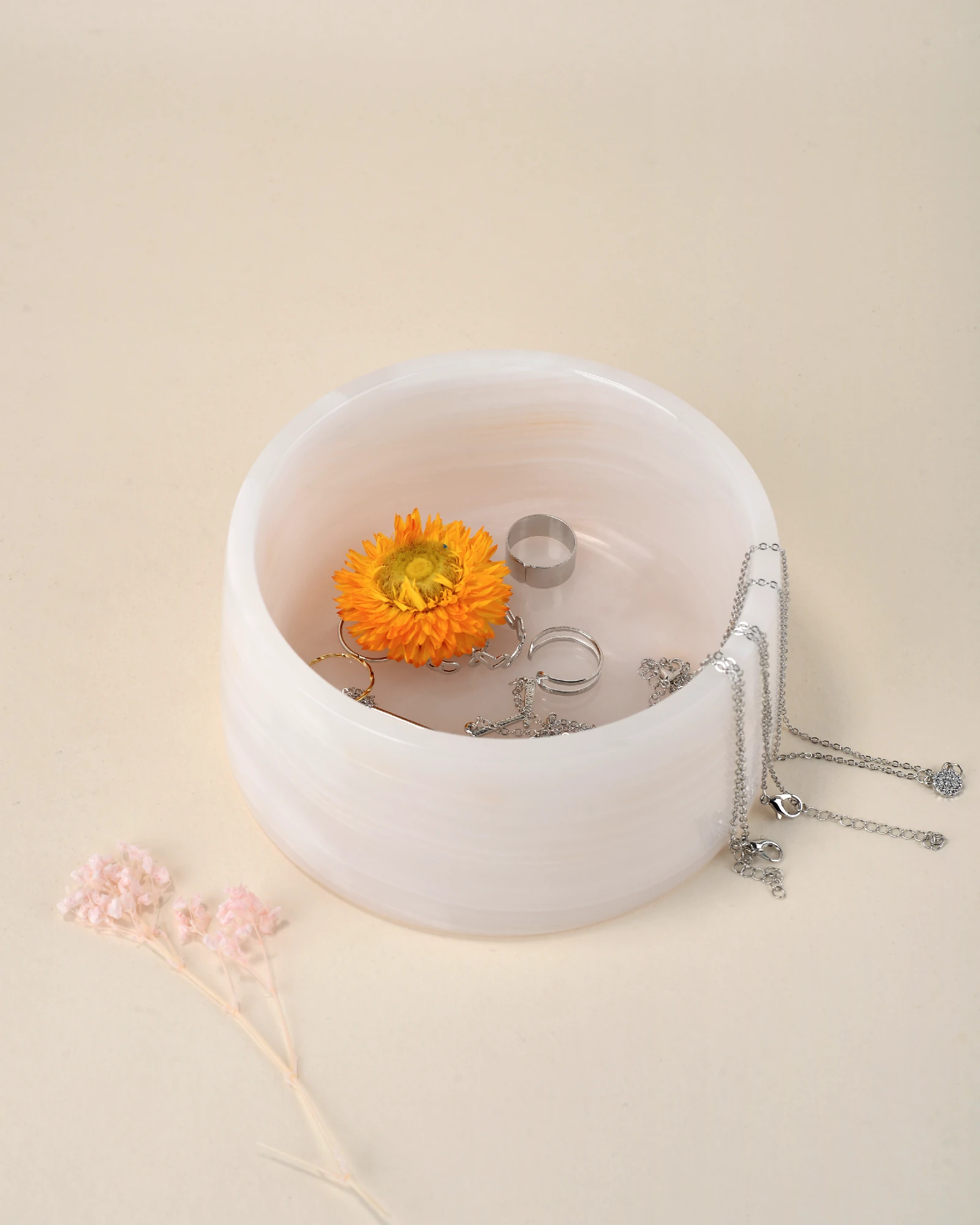 Jewelry displayed inside a 14.5cm x 6.5cm Pink Onyx decorative bowl with soft white and yellow veining