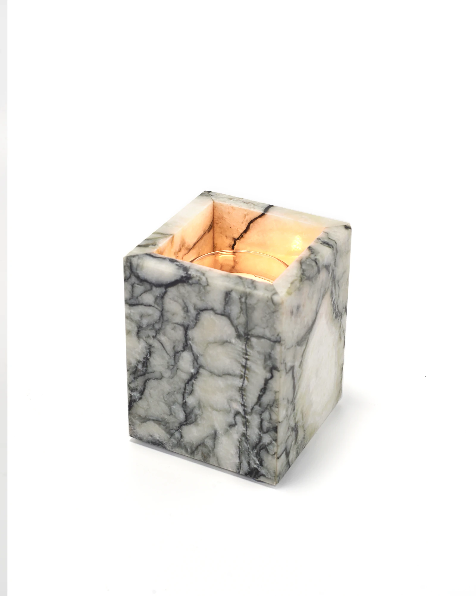 Lit candle inside jade marble holder reflecting flame on polished surface