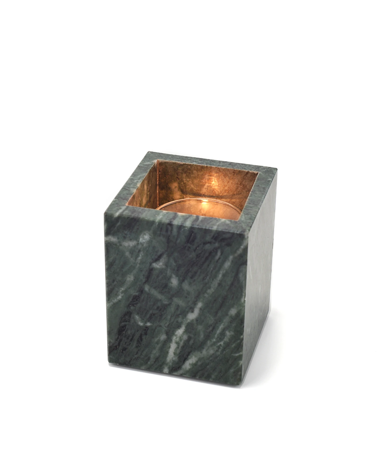 Lit candle inside green marble holder with flame reflecting on polished surface