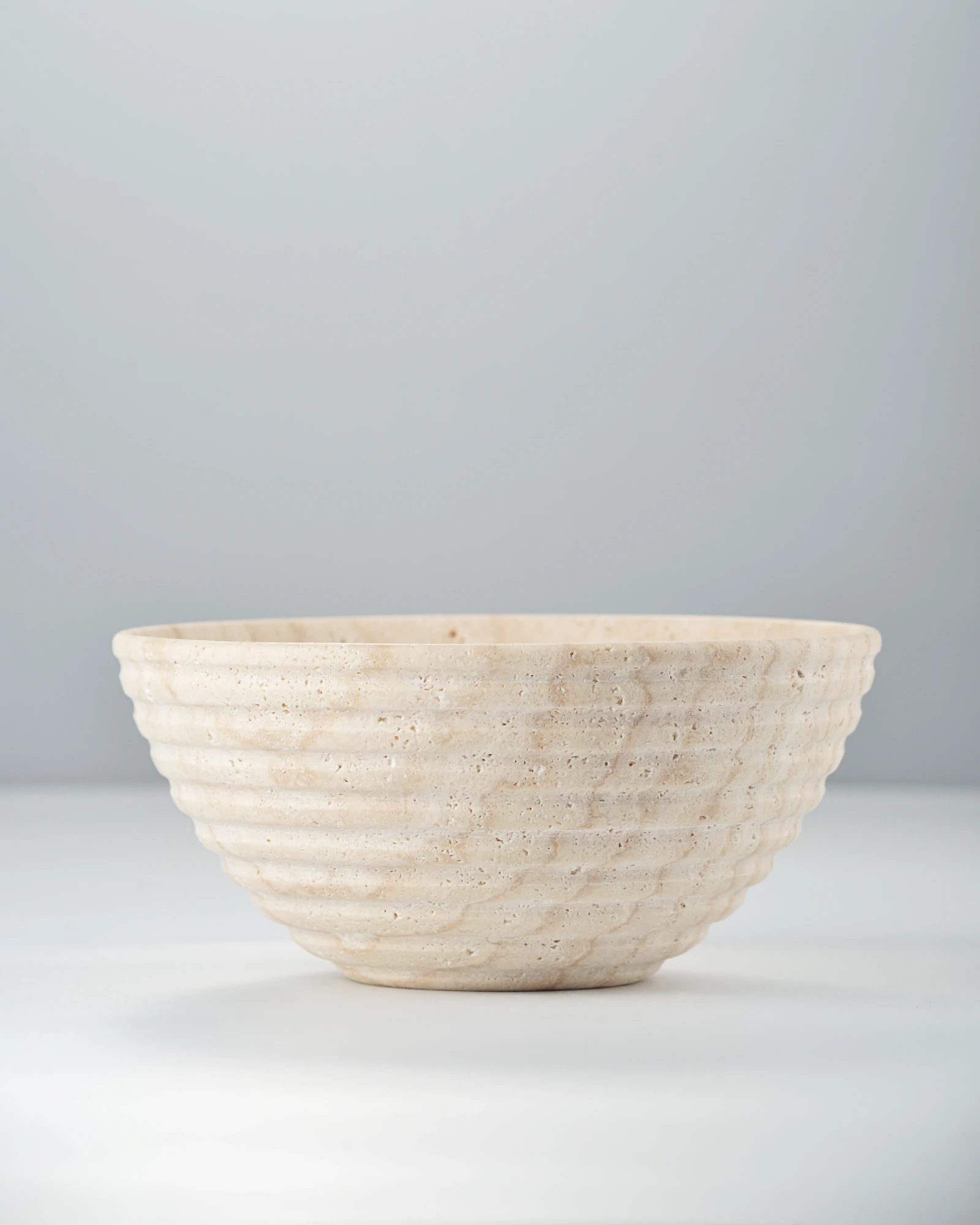 Side view of travertine bowl with grooved exterior and light-shadow details