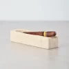 Travertine cigar ashtray with cigar placed on glossy table, creating a reflection