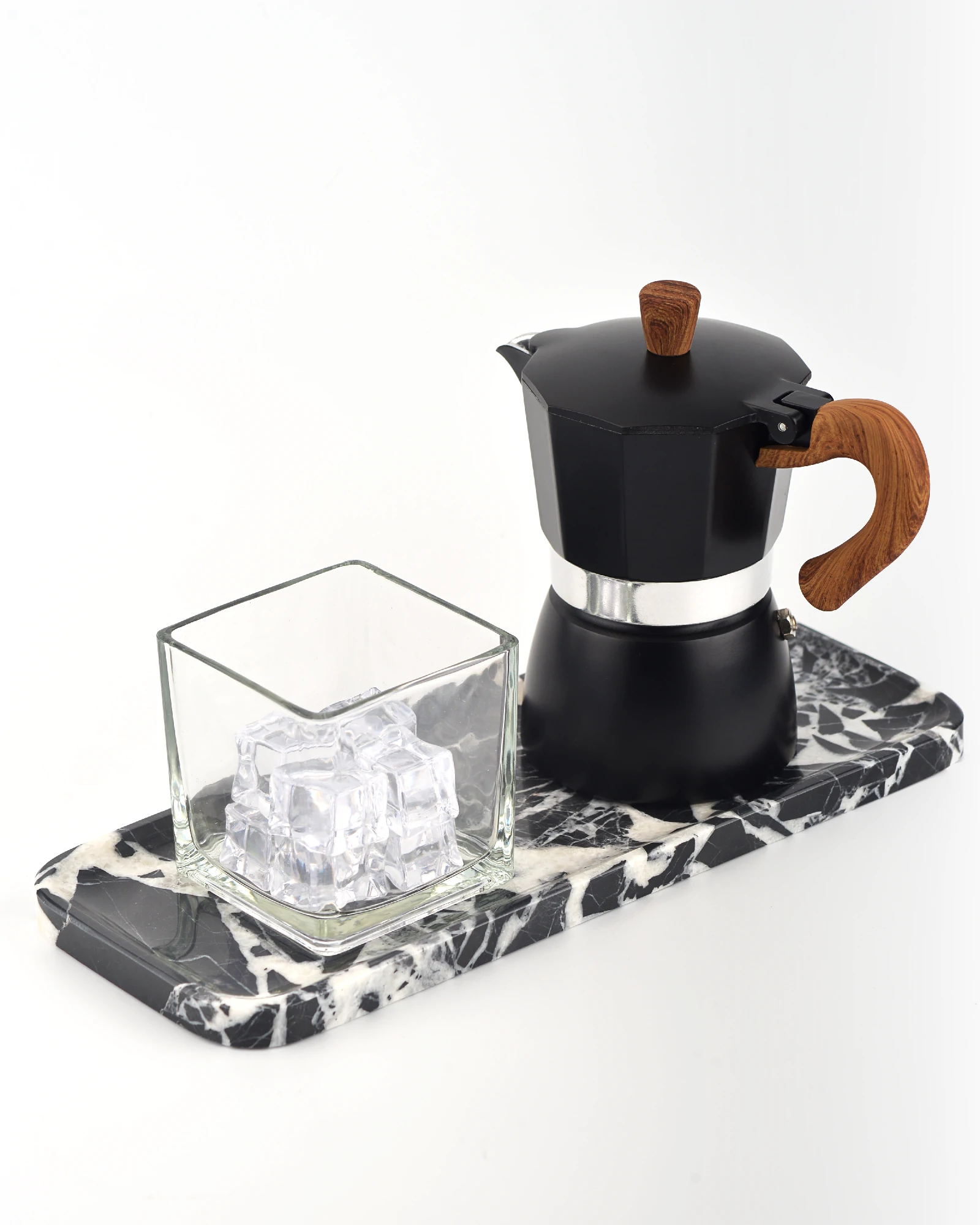 Coffee pot and glass cup arranged on black marble tray
