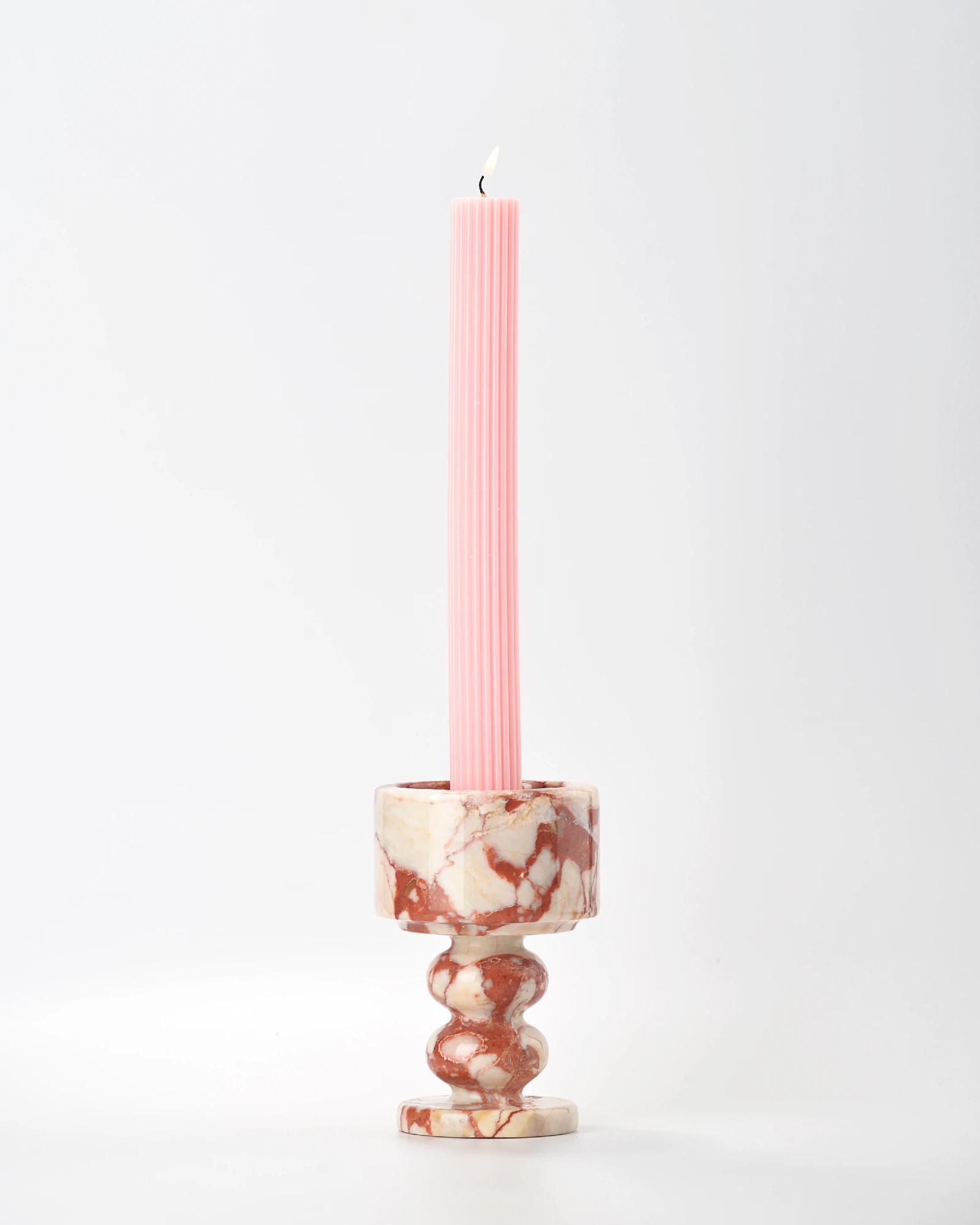 Marble candle holder with lit pink taper candle in classic setting