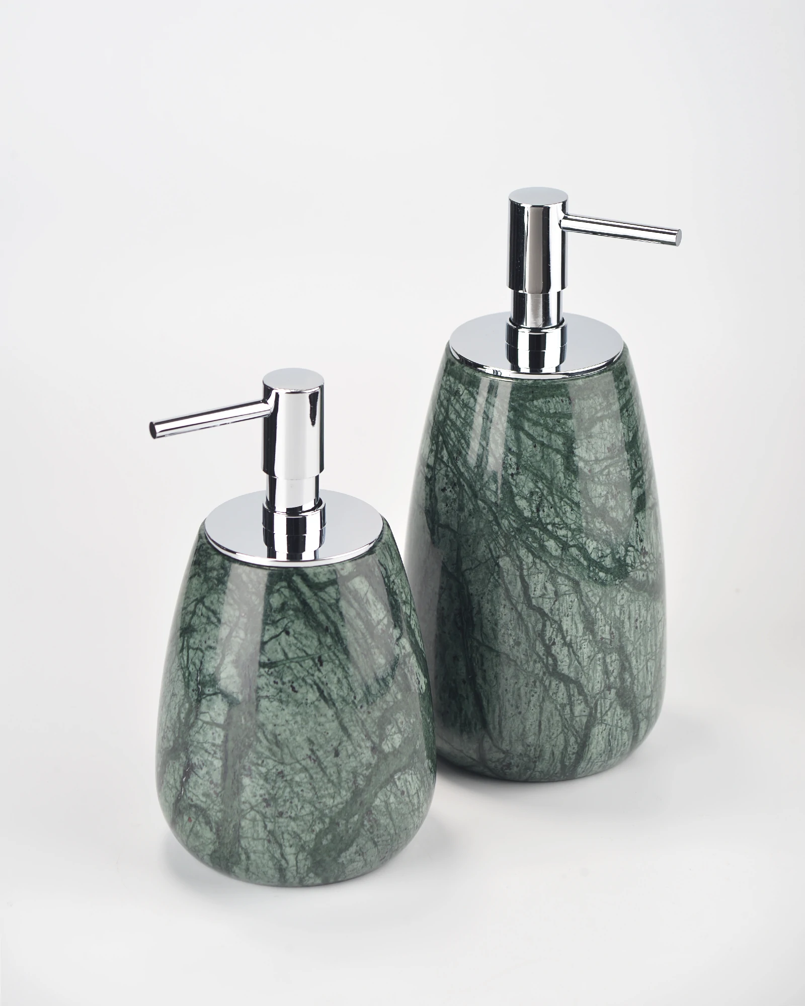 Green marble soap dispensers with chrome-finish pump heads under lighting