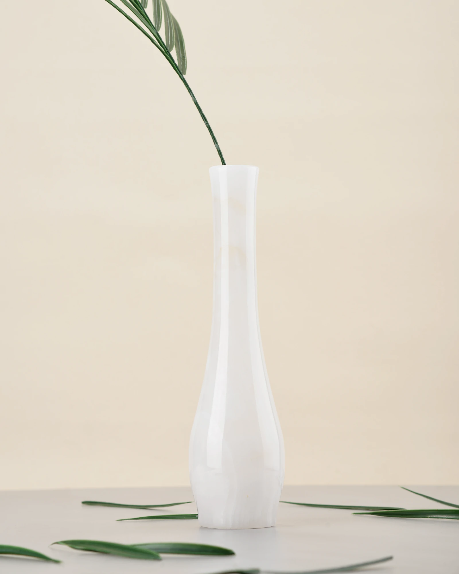 White onyx vase with palm branch in a serene minimalist setting