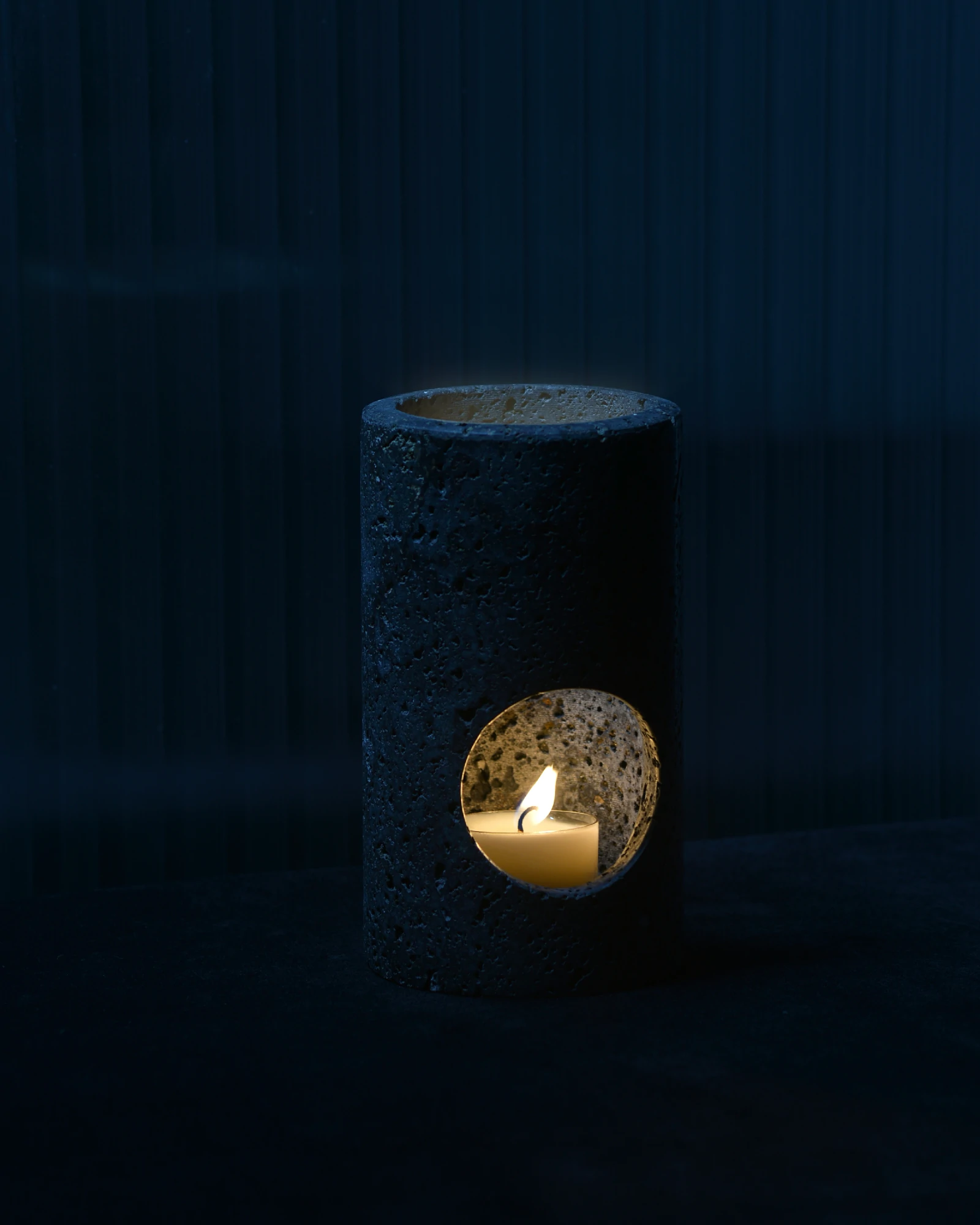Black Travertine Candle Holder glowing at night with warm candlelight