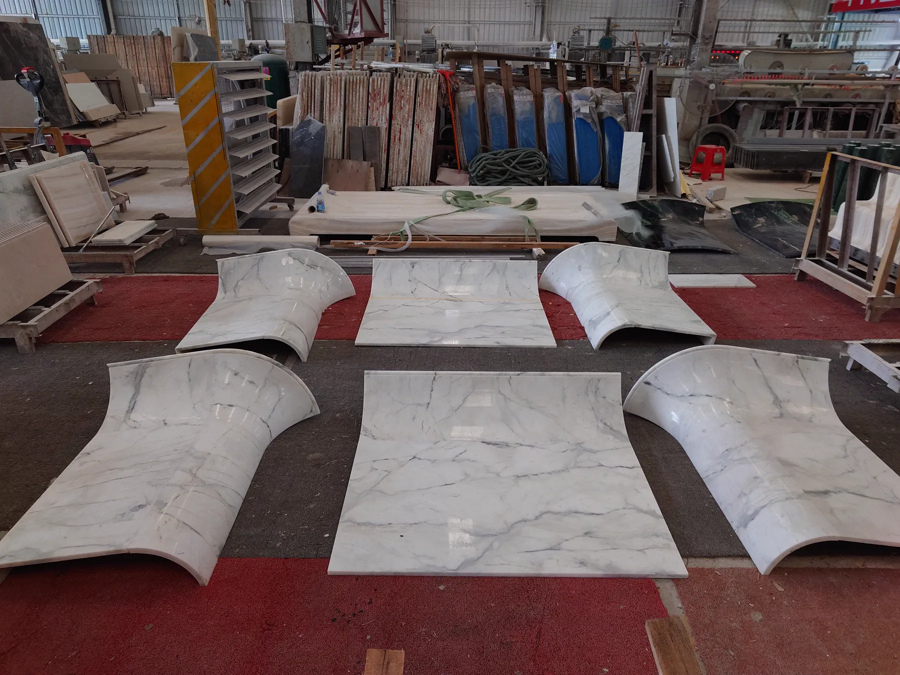 Fish Belly White curved and straight counter panels arranged on the factory floor.