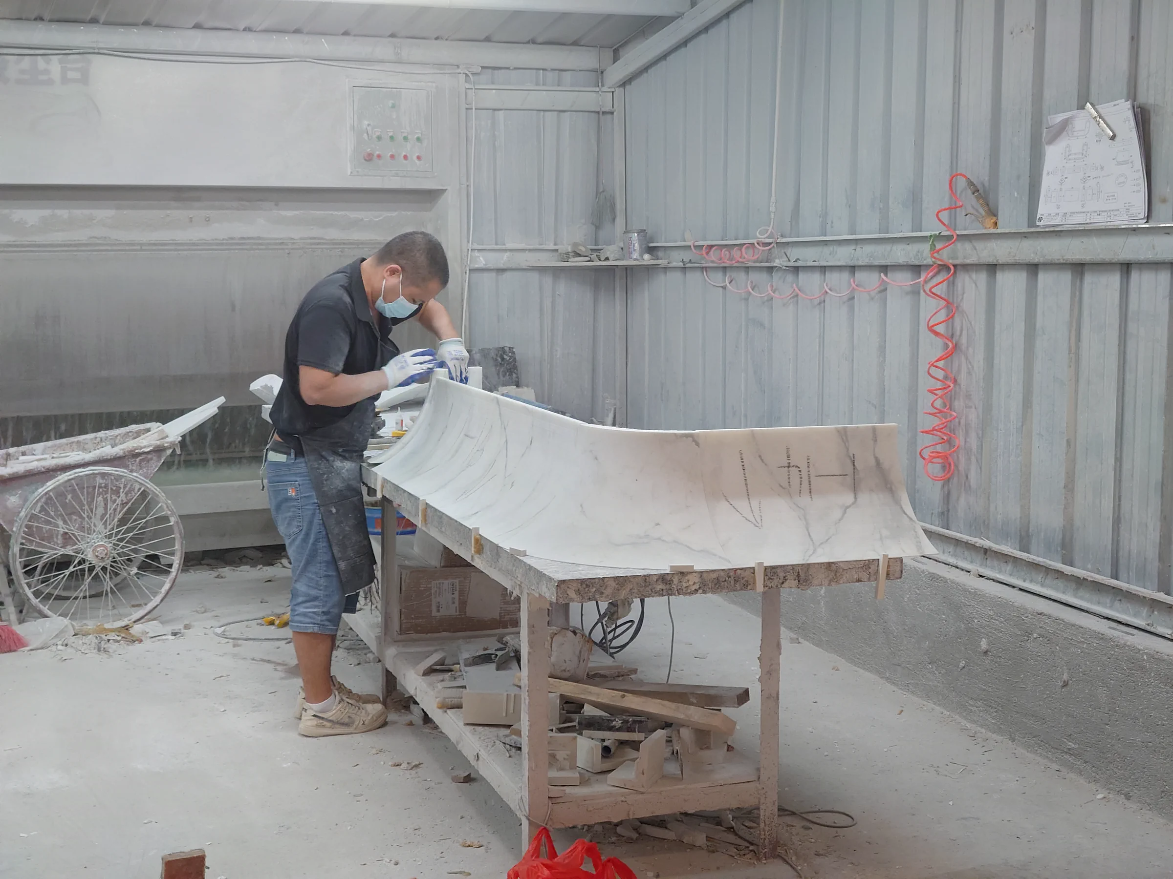 Craftsman checking carved Fish Belly White marble parts during trial assembly.