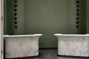 Two completed curved Fish Belly White marble reception counters in a green interior.