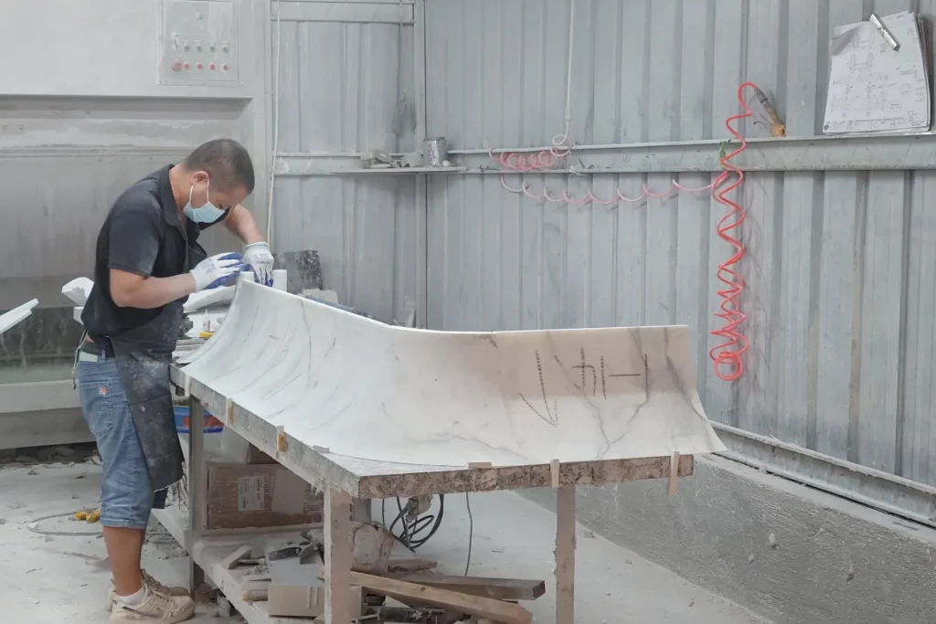 A craftsman checks a curved marble counter component during trial assembly.