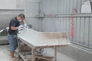 A craftsman checks a curved marble counter component during trial assembly.