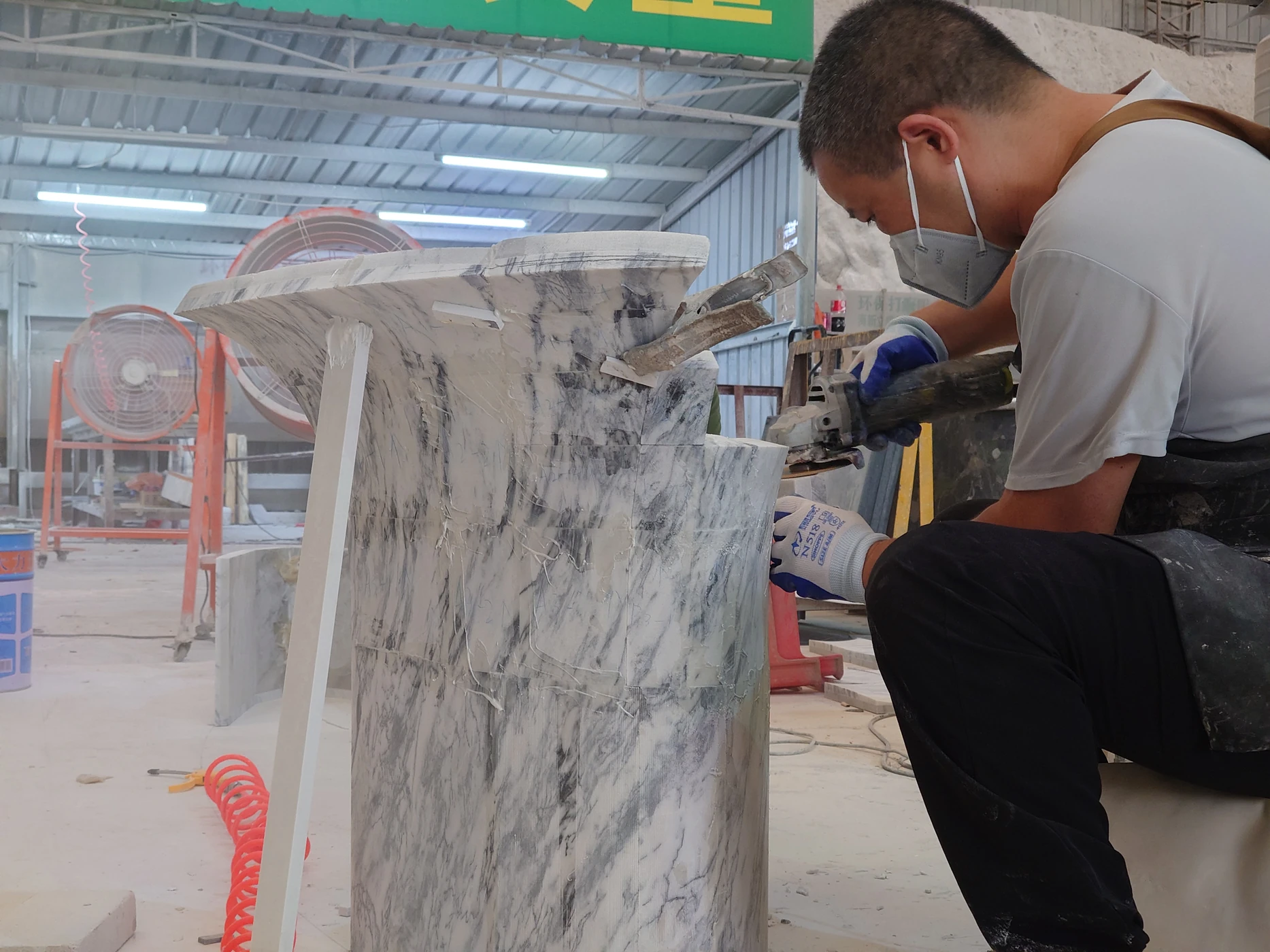Fabricator assembling curved marble panels with an angle grinder