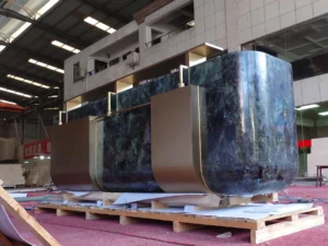Completed Lemurian Blue granite reception desk assembled with champagne-gold metalwork in the factory
