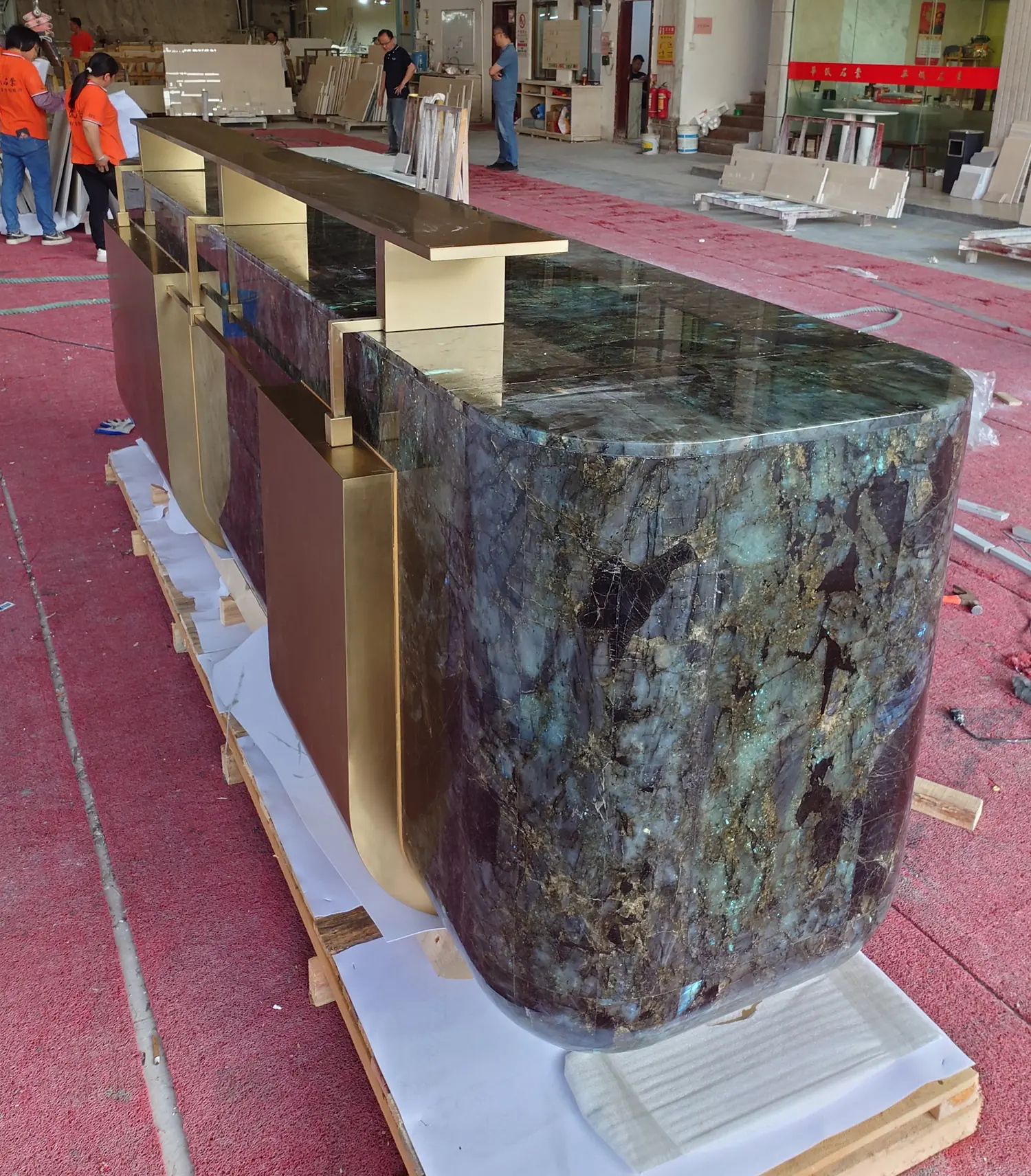 Close factory view of the reception desk top, rounded granite end and champagne-gold metal details