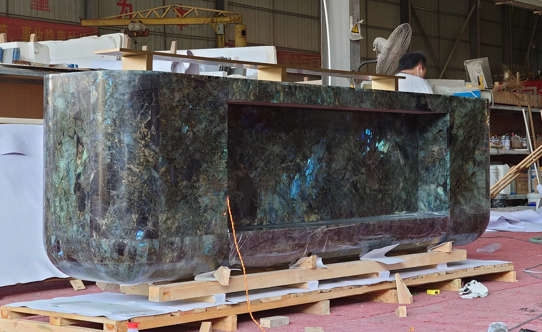 Factory daylight view showing blue and teal iridescent flashes across the Lemurian Blue granite reception desk